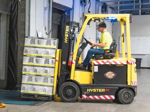 Man using Hyster 50 forklift in warehouse to load pallet into a trailer